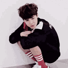a young boy wearing red and white striped socks is squatting on the floor