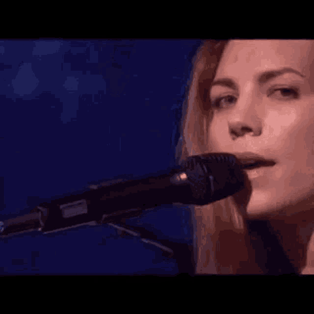 a close up of a woman singing into a microphone on stage .