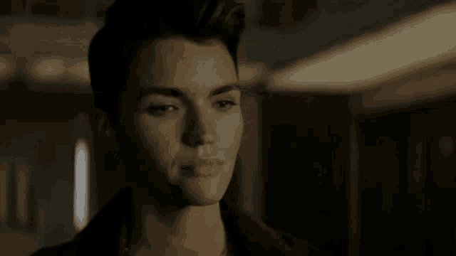 a close up of a woman 's face in a dark room looking at the camera .