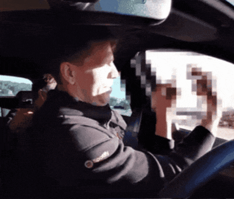 a man in a black jacket with the word spotify on the sleeve is driving a car