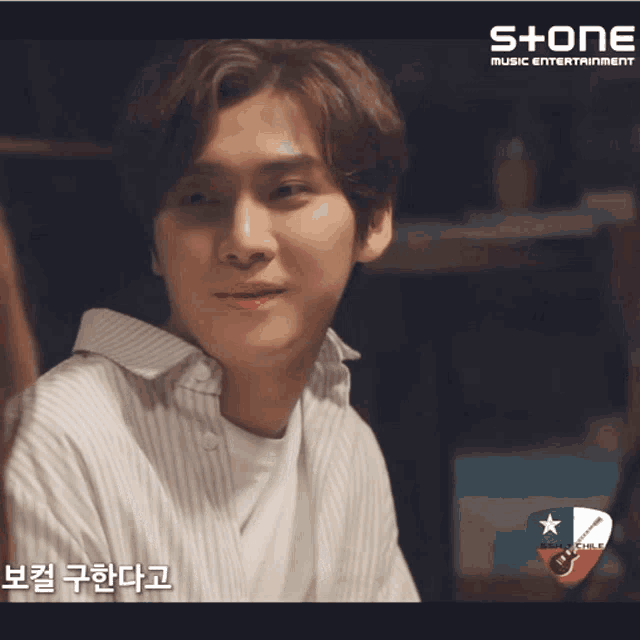 a man in a striped shirt is smiling in front of a sign that says stone music entertainment