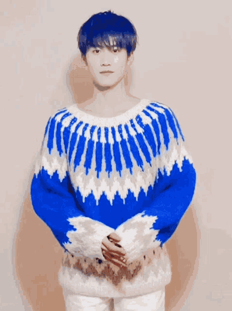 a man with blue hair is wearing a blue and white sweater and white pants