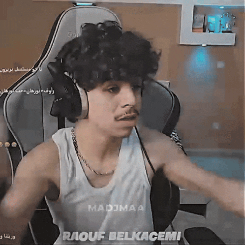 a man wearing headphones and a tank top that says madjmaa raouf belkacemi