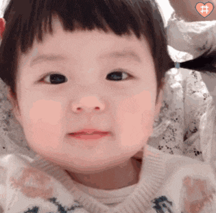 a close up of a baby 's face with a heart on the bottom right corner .
