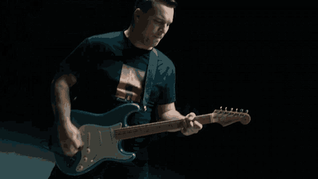 a man playing a guitar with a t-shirt that has a picture of a man on it