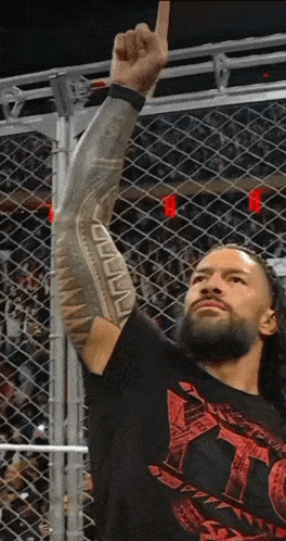 a wrestler with a tattoo on his arm holds up his fist in the air