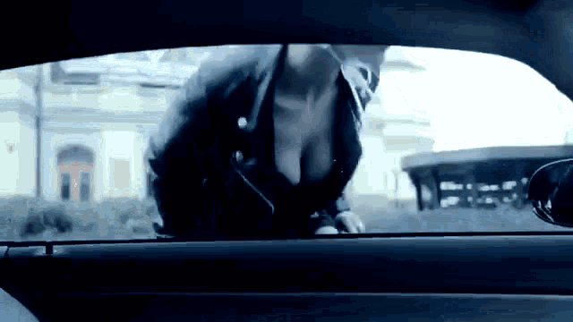 a woman in a black jacket is standing in a car