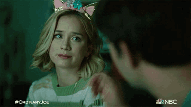 a girl wearing a cat ear headband is talking to a man ..