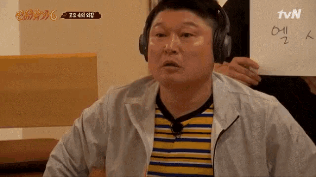 a man wearing headphones holds a piece of paper that says tvn