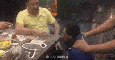 a group of people are sitting at a table with a man sitting at the table .