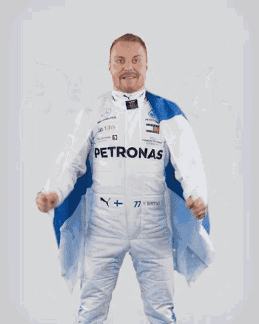a man in a petronas racing suit holds a finland flag