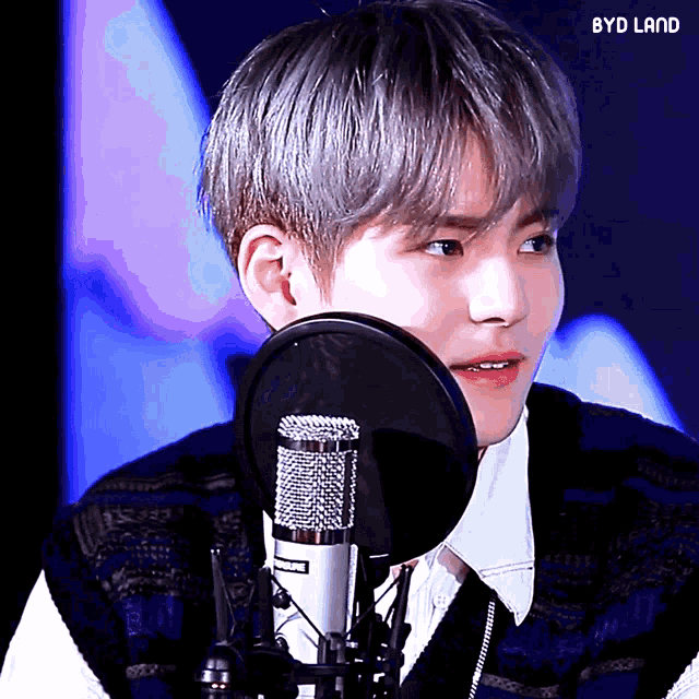 a close up of a person in front of a microphone with byd land written on the bottom left