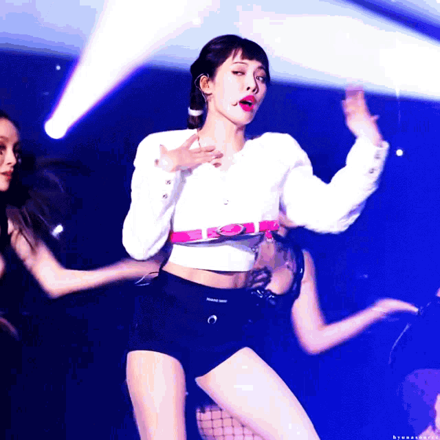 a woman in a white crop top and black shorts is dancing on stage
