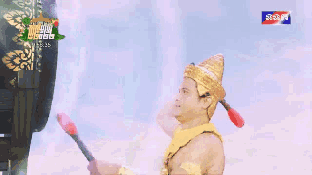 a man in a gold costume is holding a stick in front of a sign that says ' cambodia ' on it