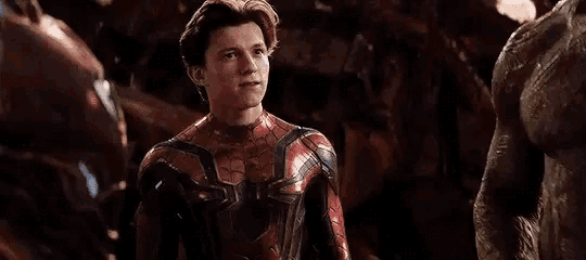 a close up of a man in a spiderman suit standing next to a man in a suit .