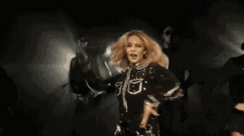 a woman is dancing on stage with her arms in the air .