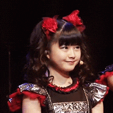 a young girl with red bows in her hair is smiling .