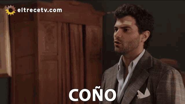 a man with a bandage on his forehead stands in front of a sign that says cono