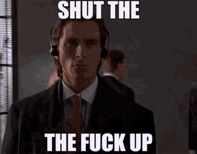 a man in a suit and tie is wearing headphones and says shut the fuck up