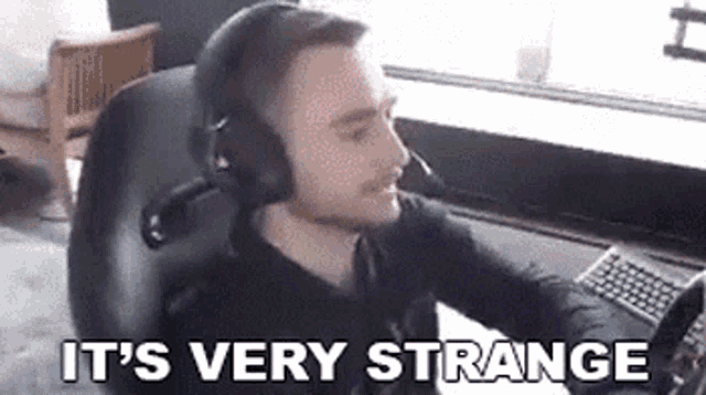 a man wearing headphones is sitting in a chair with the words `` it 's very strange '' above him .