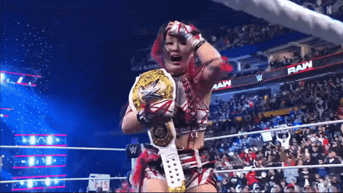 a woman in a wrestling ring holding a wrestling championship belt
