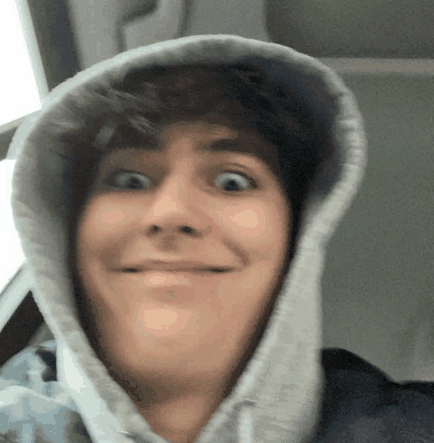a man wearing a hooded sweatshirt makes a funny face