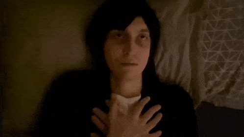 a man is laying on a bed with his hands on his chest and his eyes closed .