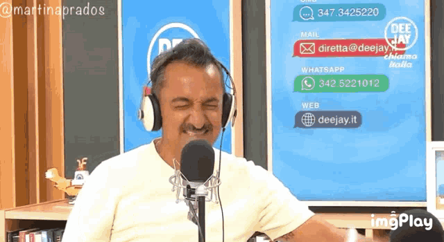 a man wearing headphones stands in front of a microphone with a sign behind him that says deejay italia