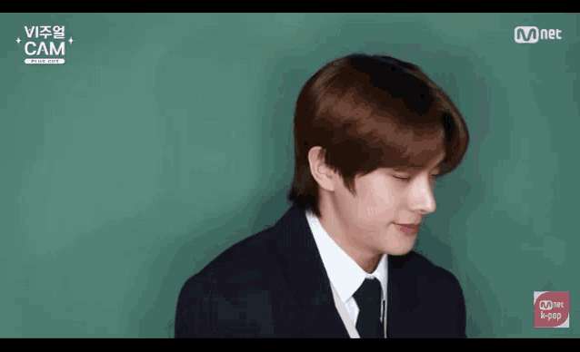 a man in a suit and tie is making a heart shape with his fingers