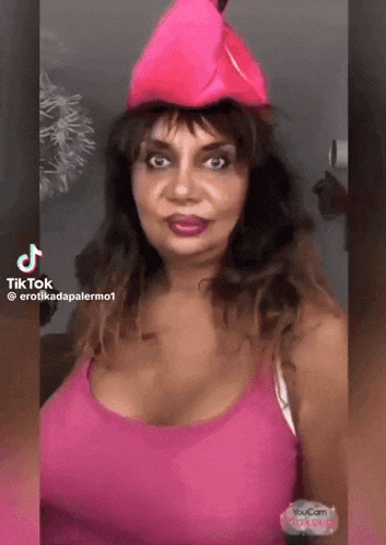 a woman wearing a pink hat and a pink tank top is making a funny face .