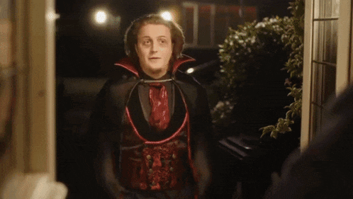 a man in a vampire costume is standing in front of a doorway