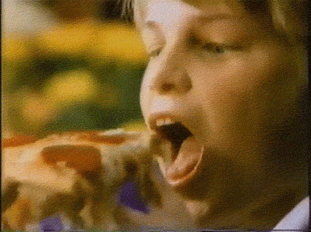 a person eating a slice of pizza with their mouth wide open