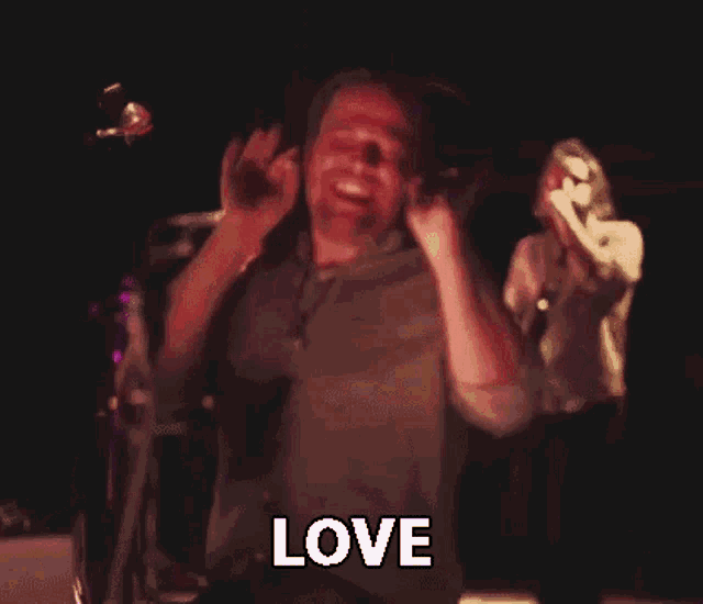 a man with a beard is laughing and saying `` love '' while dancing on a stage .