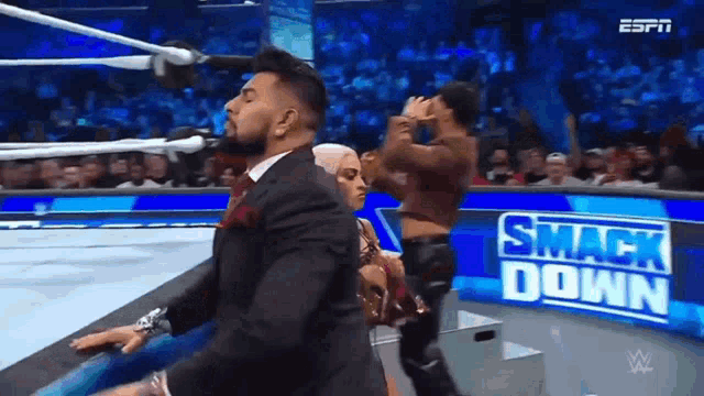 a man in a suit is dancing on a stage in front of a sign that says smack down