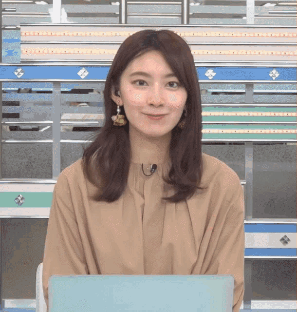 a woman wearing earrings and a microphone is smiling
