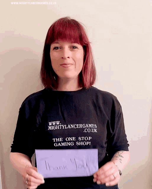 a woman wearing a mightylancergames t-shirt is holding a thank you card