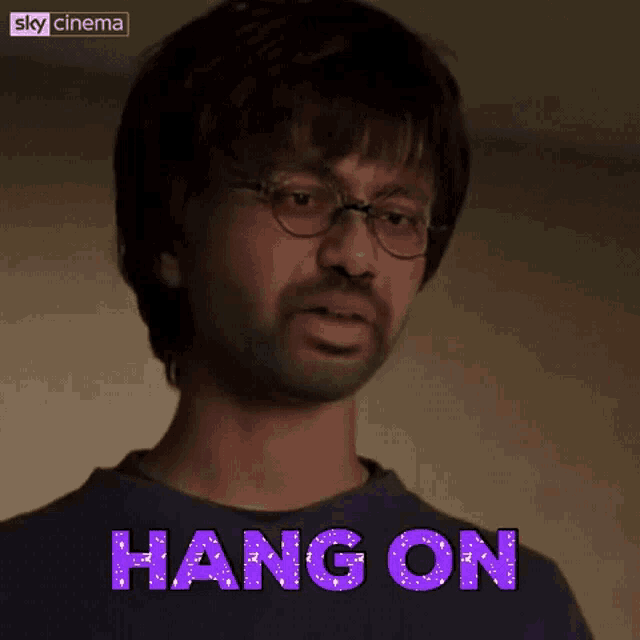 a man with glasses and the words hang on behind him