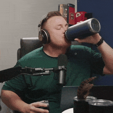a man wearing headphones is drinking from a blue yeti cup