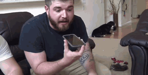 a man with a tattoo on his arm holds up a cell phone
