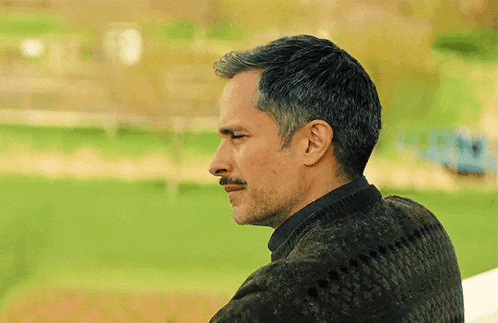 a man with a mustache is wearing a sweater and looking to the side
