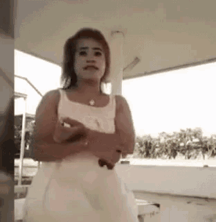 a woman in a white dress is standing under a canopy and looking at the camera .
