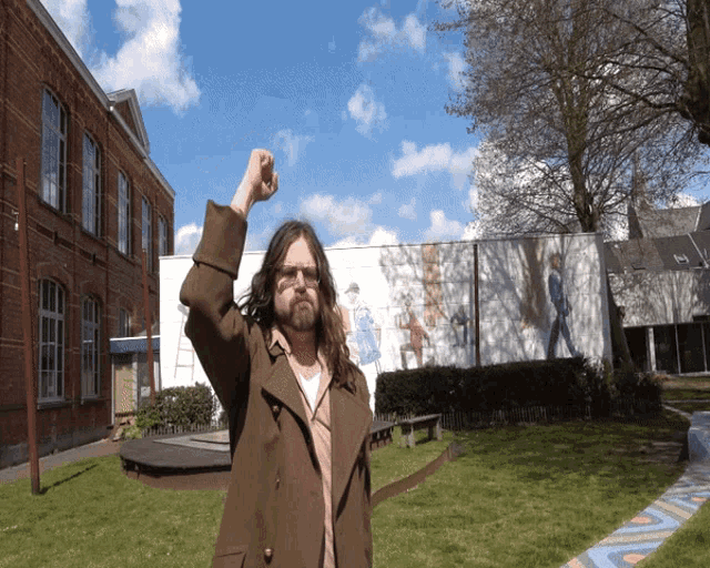 a man in a brown coat holds up his fist