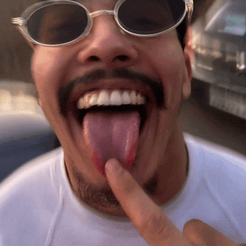 a man wearing sunglasses has his tongue out