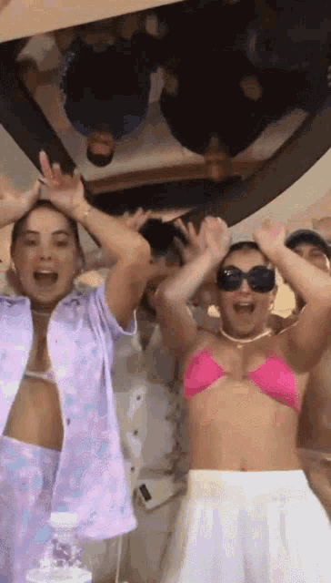 a group of people are dancing in a room with a woman in a pink bikini top .