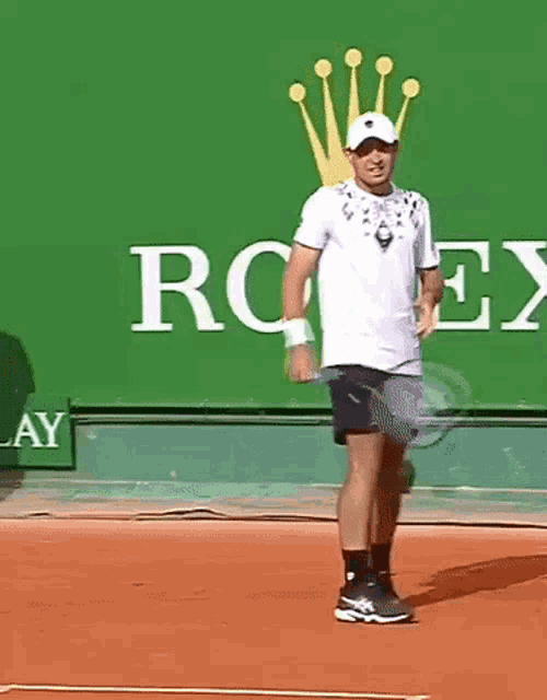 a man is dancing on a tennis court in front of a large rolex sign