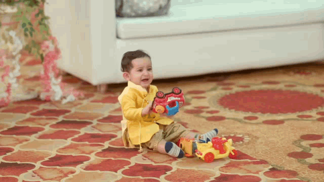 a little boy is sitting on the floor playing with a toy truck