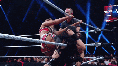 two women are wrestling in a ring and one of them is wearing a red and black outfit