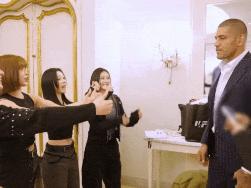 a man in a suit stands in front of a group of women