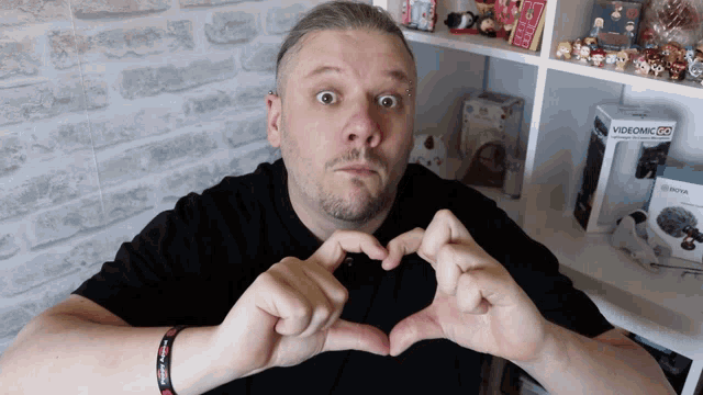 a man is making a heart shape with his hands in front of a videomic box