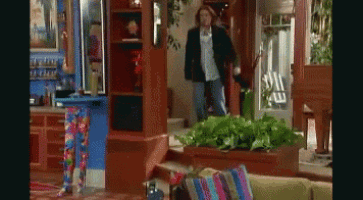 a man in a black jacket stands in a living room with a couch